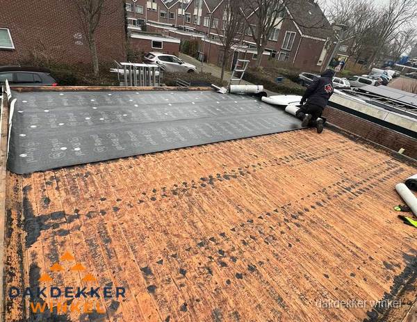 Dakdekker legt onderlaag op plat dak met houten constructie in Winkel Dakdekker legt onderlaag op plat dak met houten constructie in Winkel