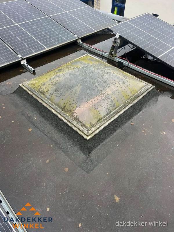 Vervuilde lichtkoepel op plat dak met zonnepanelen in Winkel Vervuilde lichtkoepel op plat dak met zonnepanelen in Winkel