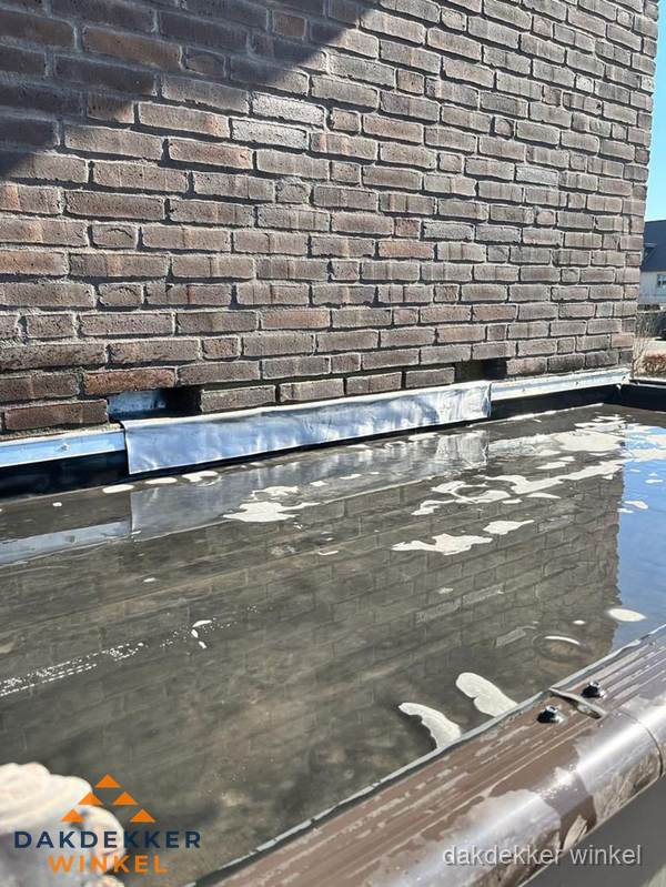 Stilstaand water op plat dak door slechte afwatering in Winkel