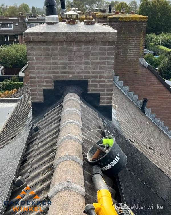 Schoorsteen met loodaansluiting en nokvorst op pannendak in Winkel