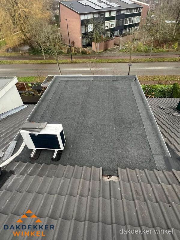 Plat dak inspectie met bitumen bedekking naast schuin pannendak in Winkel Plat dak inspectie met bitumen bedekking naast schuin pannendak in Winkel