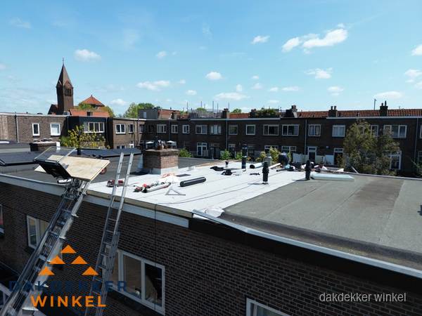 Dakdekkers aan het werk op plat dak in Winkel