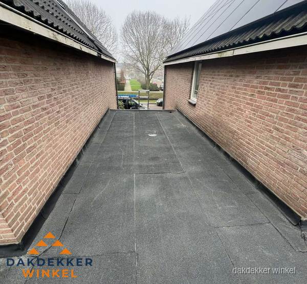 Plat dak met bitumen dakbedekking tussen bakstenen muren in Winkel Plat dak met bitumen dakbedekking tussen bakstenen muren in Winkel
